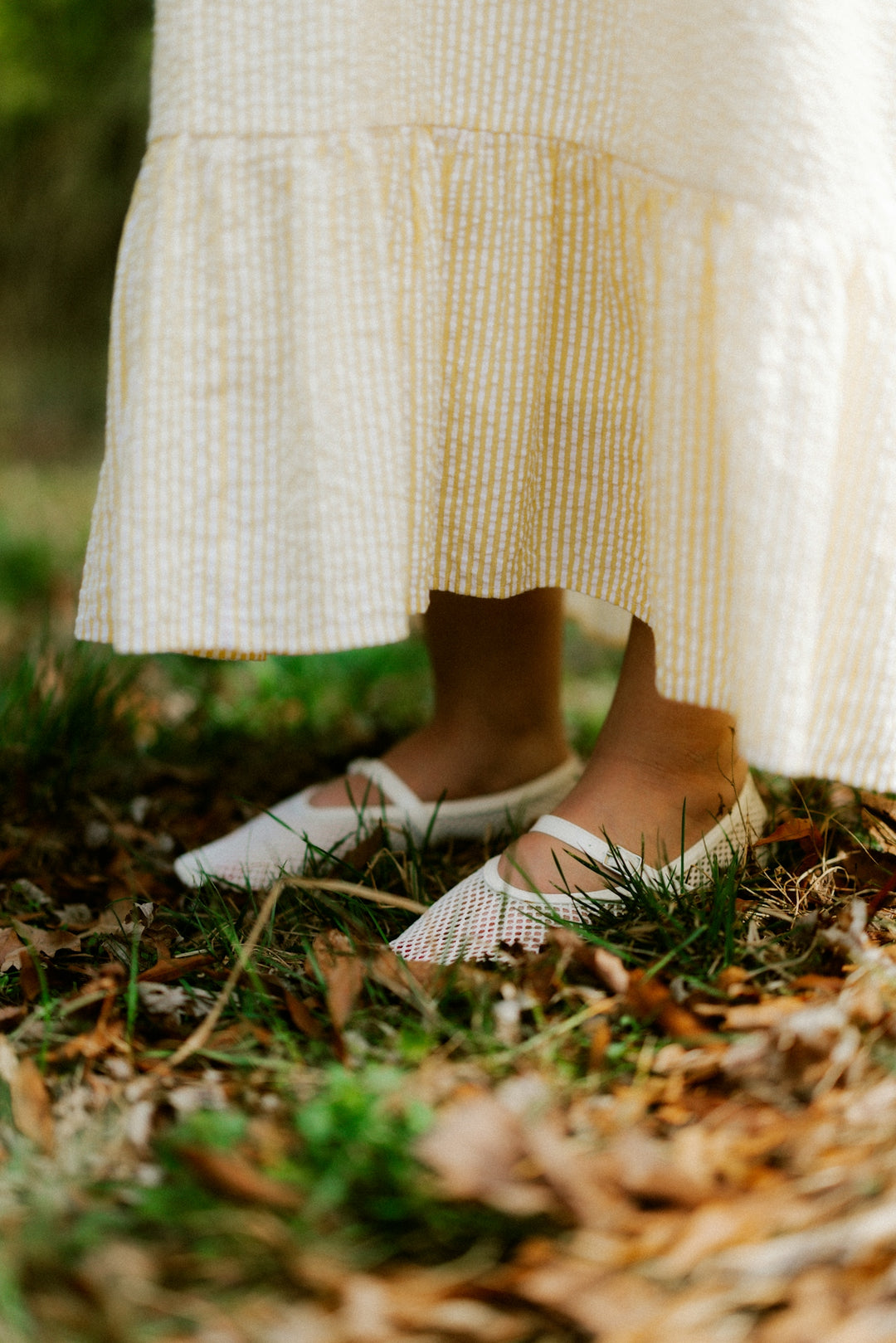 Child's feet in white shoes under a yellow dress